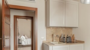 Una cocina moderna con armarios blancos, un lavamanos en la encimera y diversos utensilios de cocina.