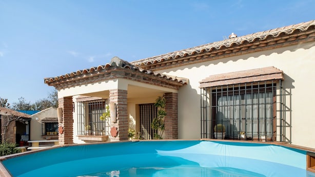 Une piscine dotée d’un toit carrelé, d’une façade en briques et d’une fenêtre ornée d’une grille métallique.