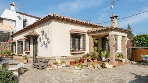 Un bâtiment traditionnel avec un toit en tuiles, des plantes en pot et une terrasse en pierre.