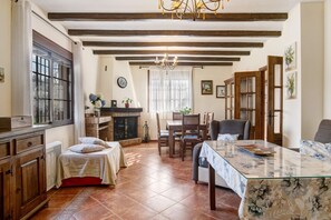 Une pièce comprenant un lit, une table à manger, des chaises, une cheminée et un lustre.