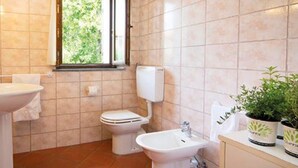 Ein Badezimmer mit Waschbecken, Toilette, Bidet und Topfpflanzen.