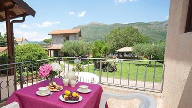 Ein Balkon mit Frühstückstisch, Stuhl und Blick auf die umliegende Landschaft.