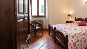 A bedroom with a bed, a chair, a window, and a radiator. - Apartment 'Ciclamino' with Shared Pool, Shared Garden and Wi-Fi (Campochiesa)