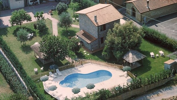 An aerial view of a residential area with a swimming pool, a fenced garden, and a small building with a tiled roof. - Apartment 'Ciclamino' with Shared Pool, Shared Garden and Wi-Fi (Campochiesa)