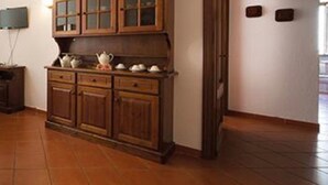 A kitchen with wooden cabinets, a countertop, and a wall-mounted television. - Apartment 'Ciclamino' with Shared Pool, Shared Garden and Wi-Fi (Campochiesa)