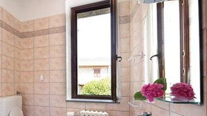 A bathroom with a toilet, sink, and a window with a view of greenery outside. - Apartment 'Dalia' with Shared Pool, Private Terrace and Wi-Fi (Campochiesa)