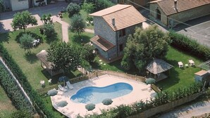 An aerial view of a residential area with a swimming pool, a fenced garden, and a small building with a tiled roof. - Apartment 'Dalia' with Shared Pool, Private Terrace and Wi-Fi (Campochiesa)