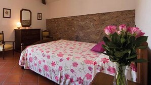 A bedroom with a bed, dresser, mirror, and a vase with flowers. - Apartment 'Dalia' with Shared Pool, Private Terrace and Wi-Fi (Campochiesa)