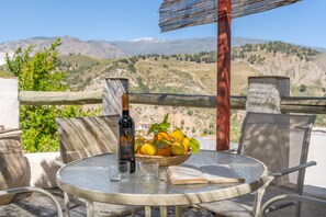 A round table with a bottle, glasses, a bowl of fruit, and an open book. - Country House 'Casa El Concejo' with Mountain Views, Wi-Fi, and Air Conditioning (Cónchar)