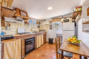 A kitchen with a gas stove, oven, and a microwave. There is a dining table with a basket of lemons. - Country House 'Casa El Concejo' with Mountain Views, Wi-Fi, and Air Conditioning (Cónchar)