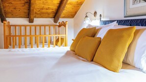 A bedroom with a wooden crib, white bedding, and yellow patterned pillows. - La Casa Di Gio - Dépendance in Villa (Viagrande)