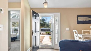 Una sala de estar con un sofá azul, una puerta que da al exterior y una silla blanca.
