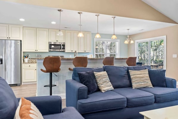 A modern kitchen with white cabinets, stainless steel appliances, and pendant lighting.
