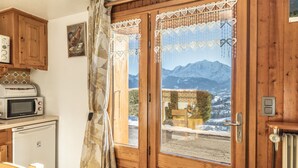 A wooden-framed door with a view of mountains, a microwave, and a refrigerator in the kitchen area.