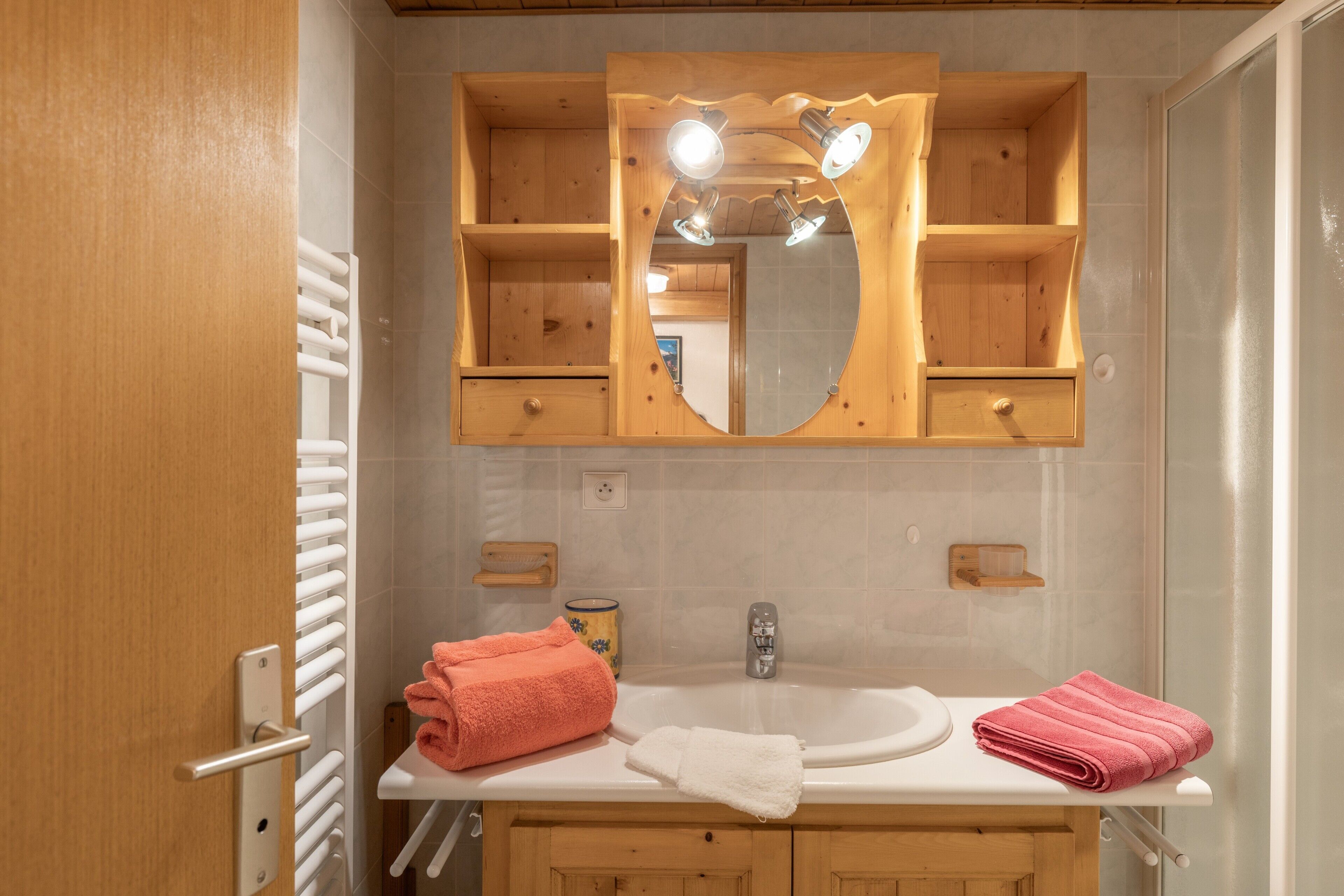 A bathroom with a wooden vanity, a sink, a mirror, and a towel rack.