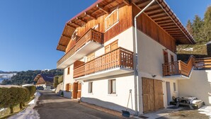 A two-story wooden building with balconies, a garage, and a snow-covered landscape.