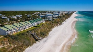 Un hotel costero con edificios de varios pisos, una playa de arena y una vista despejada del océano.
