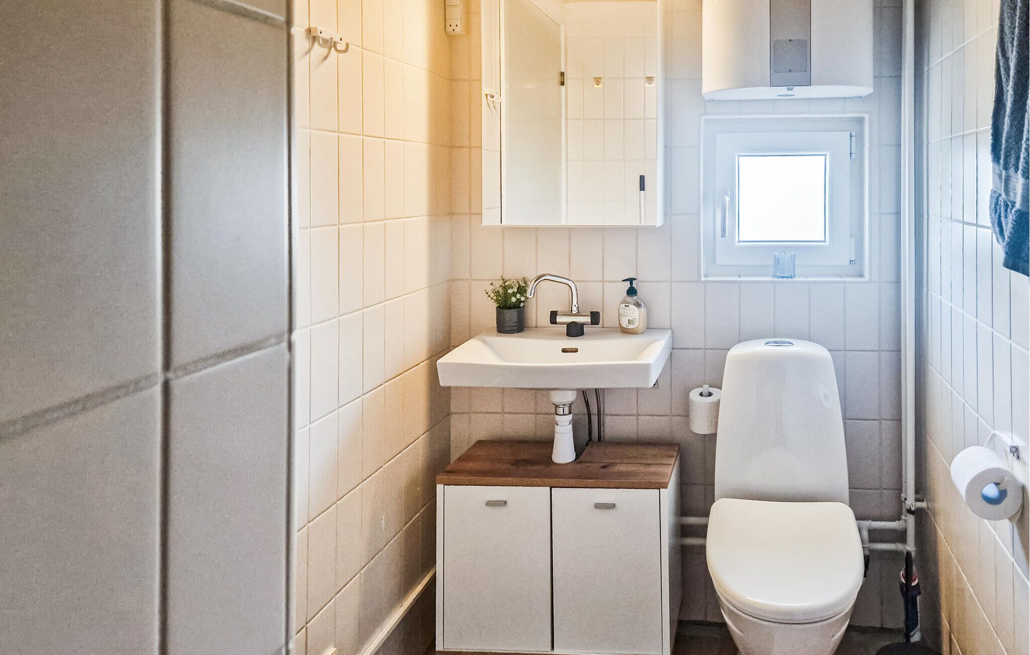 Une petite salle de bain avec un lavabo blanc, des toilettes et un petit meuble sous le lavabo.