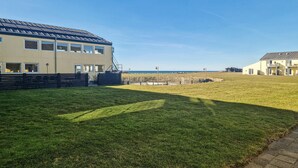A building with multiple windows and a flat roof, situated in a grassy area with a clear sky.