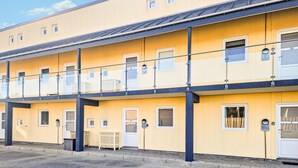 A multi-story yellow building with balconies, numbered doors, and a visible entrance.