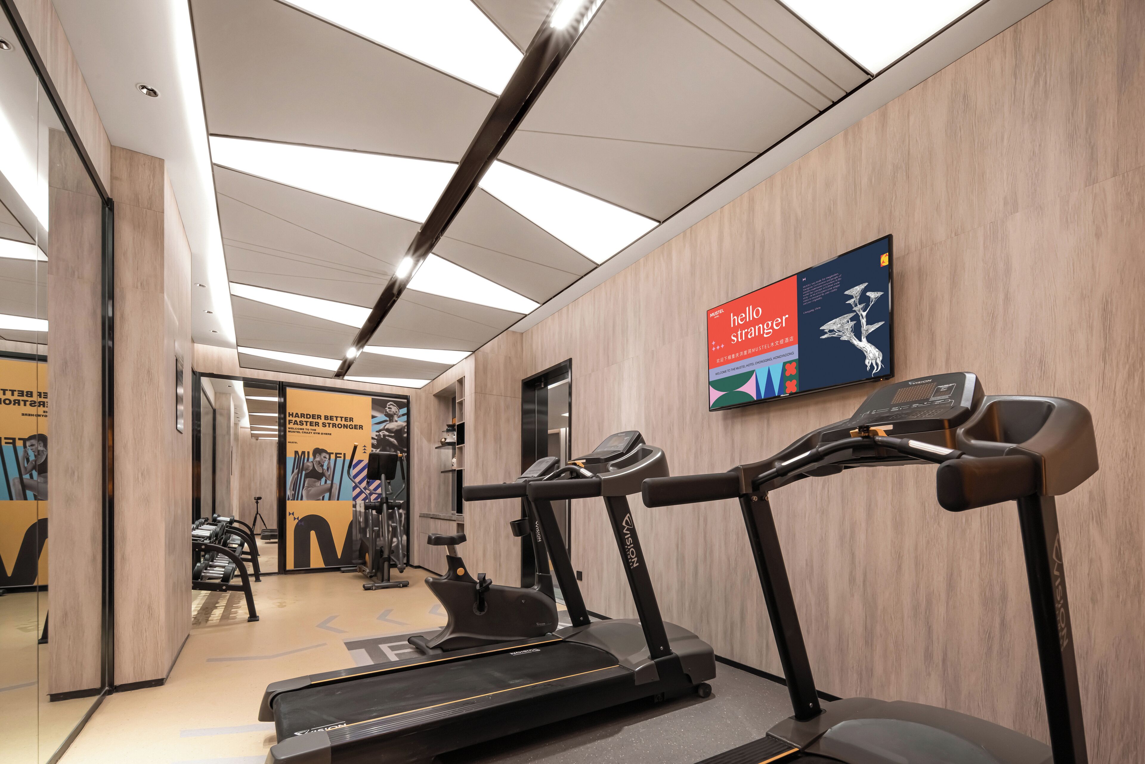 A modern gym with treadmills, a mirrored wall, and motivational posters.