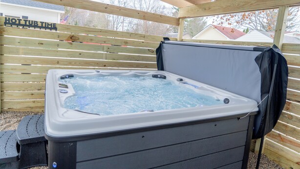 Ein Whirlpool mit einer Holzterrasse und einem Schild mit der Aufschrift 'HOT TUB TIME'.