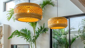 A modern dining area with a marble table, wooden chairs, and two woven pendant lights. - Villa Bayu by GORO (Seminyak)