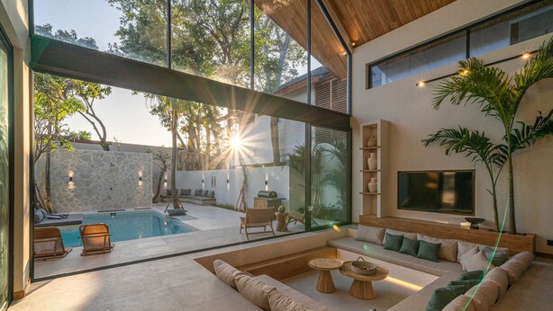 A modern living room with a large glass wall, a pool, and a comfortable seating area. - Villa Bayu by GORO (Seminyak)