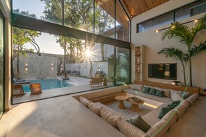 A modern living room with a large glass wall, a pool, and a comfortable seating area.