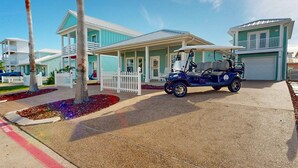 Un quartier résidentiel avec des maisons, un petit véhicule électrique pour se déplacer sur un terrain de golf et une clôture blanche en bois.