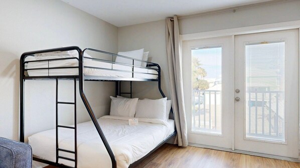 A bunk bed room with a balcony door and a view of the outside.