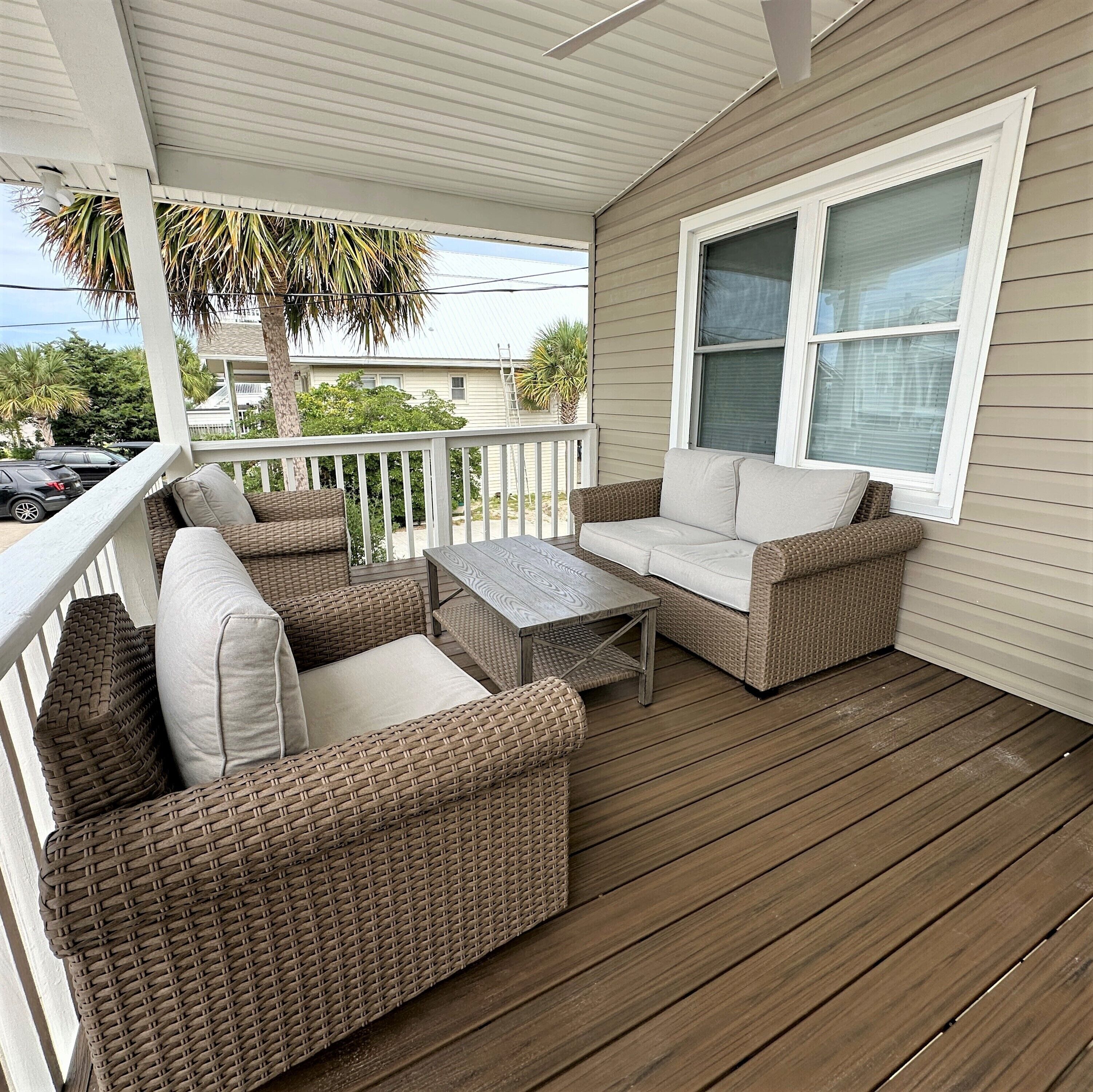 A covered porch with wicker furniture, a table, and a window.