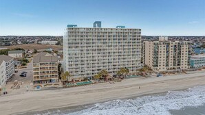 Ein Hochhaus-Hotel mit mehreren Etagen, Blick auf den Strand und einem Poolbereich.