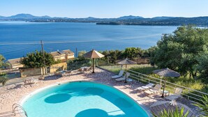 A swimming pool with a view of a large body of water and mountains in the background.