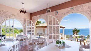 A restaurant with white furniture, large arched windows, and handwritten notes on the walls. - Apartment 'Stefanos Place Sea View' with Sea View, Wi-Fi and Air Conditioning (Corfu)