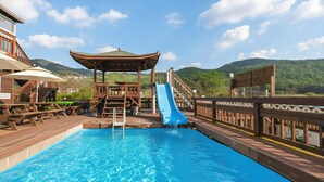A pool with a blue slide, wooden deck, and a gazebo. - Gyeongju Woojin Green Pension (Gyeongju)