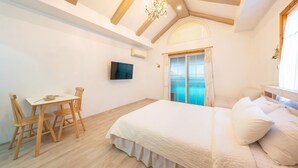 A bedroom with a bed, a desk with chairs, a TV, and a window with curtains. - Gyeongju Woojin Green Pension (Gyeongju)