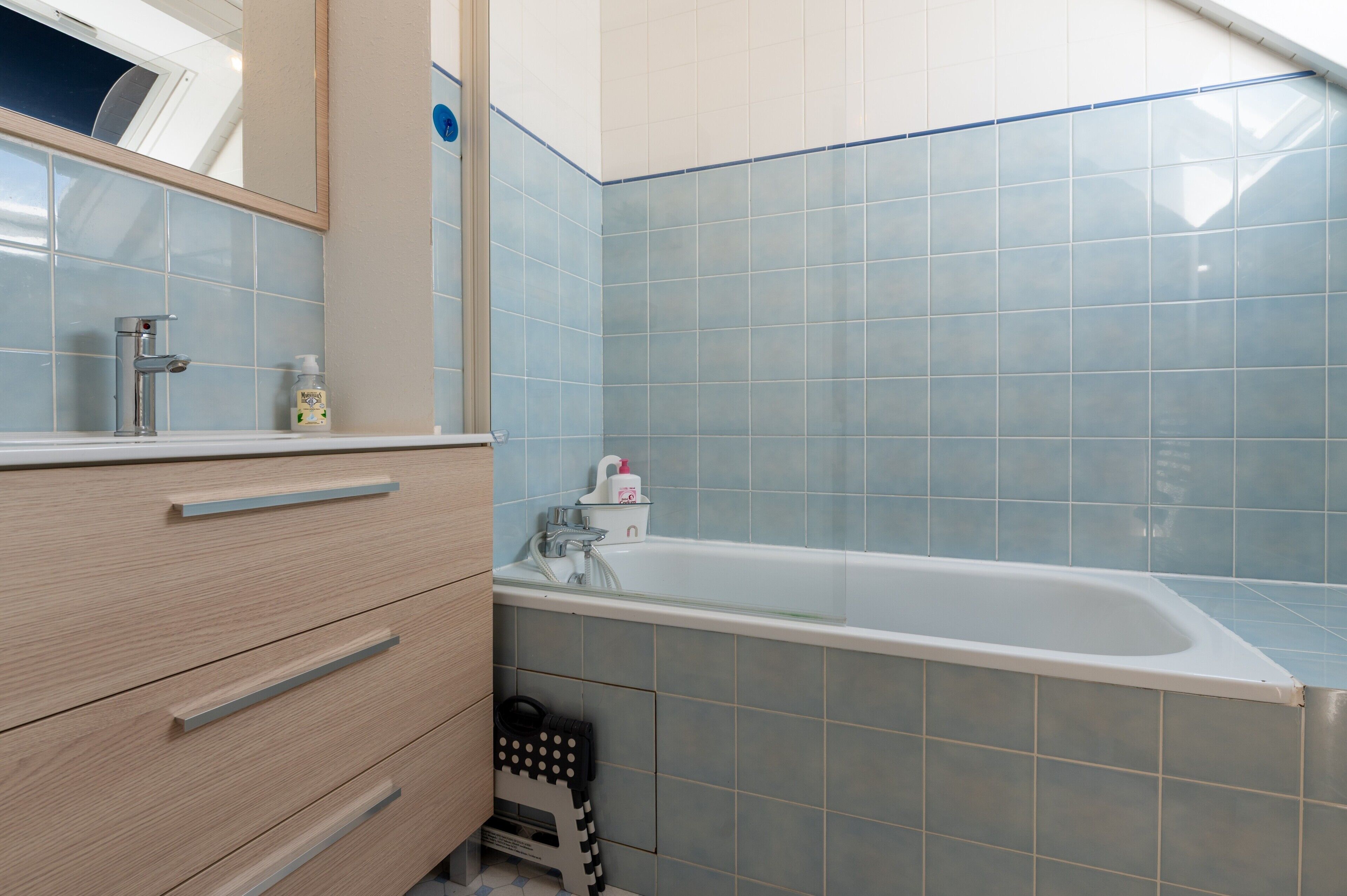 Un baño con bañera, espejo y tocador con cajones.