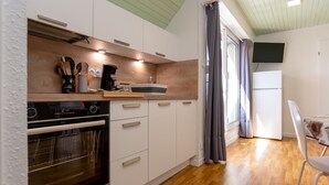 Une cuisine compacte dotée d’un four encastré, d’un téléviseur à écran plat et d’un coin repas avec une table et une chaise.