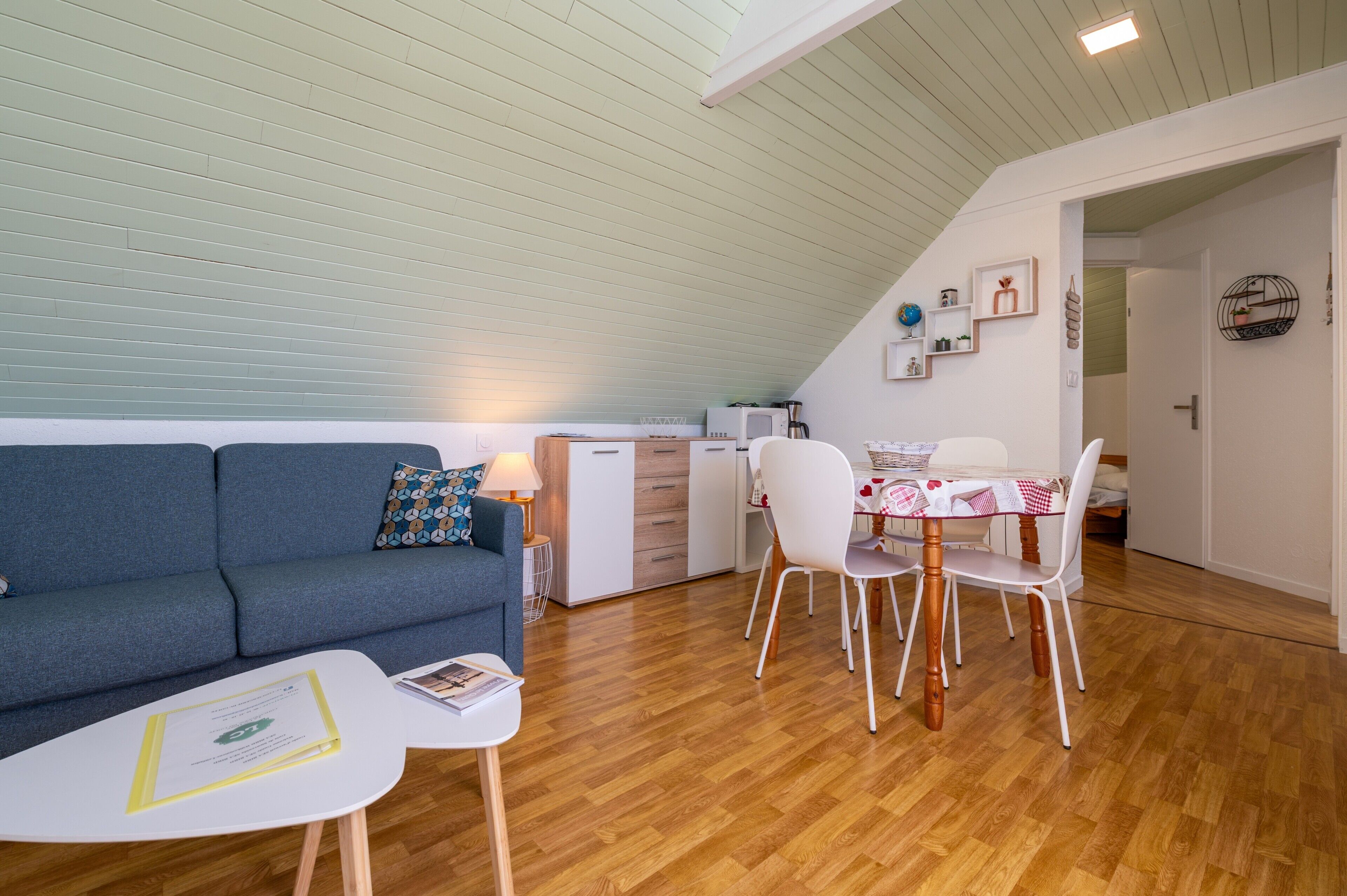 Ein modernes, kompaktes Wohnzimmer mit Essbereich, einer Küchenzeile und einer gemütlichen Sitzecke.