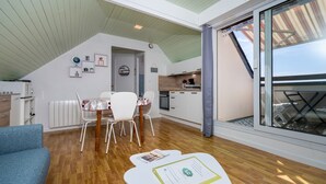Un intérieur moderne comprenant un coin repas, une cuisine et une grande porte-fenêtre coulissante donnant sur l’extérieur.