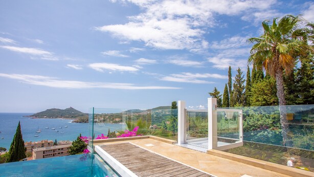 A rooftop infinity pool with a view of the sea and boats, a wooden deck, and a glass railing. - Studio 'L'Esterel' with Sea View, Wi-Fi, and Air Conditioning (Saint-Raphaël)