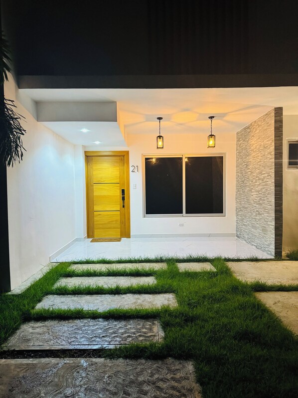 A modern house with a wooden door, two windows, and a number '21' on the wall.