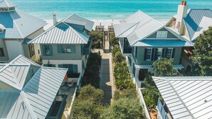 Un quartier résidentiel situé sur la côte, avec des maisons dotées de toits bleus et de murs blancs, d’une terrasse en bois et d’une vue sur l’océan.