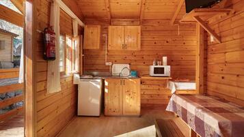 Una cabaña de madera con kitchenette, extintor, microondas y televisor.