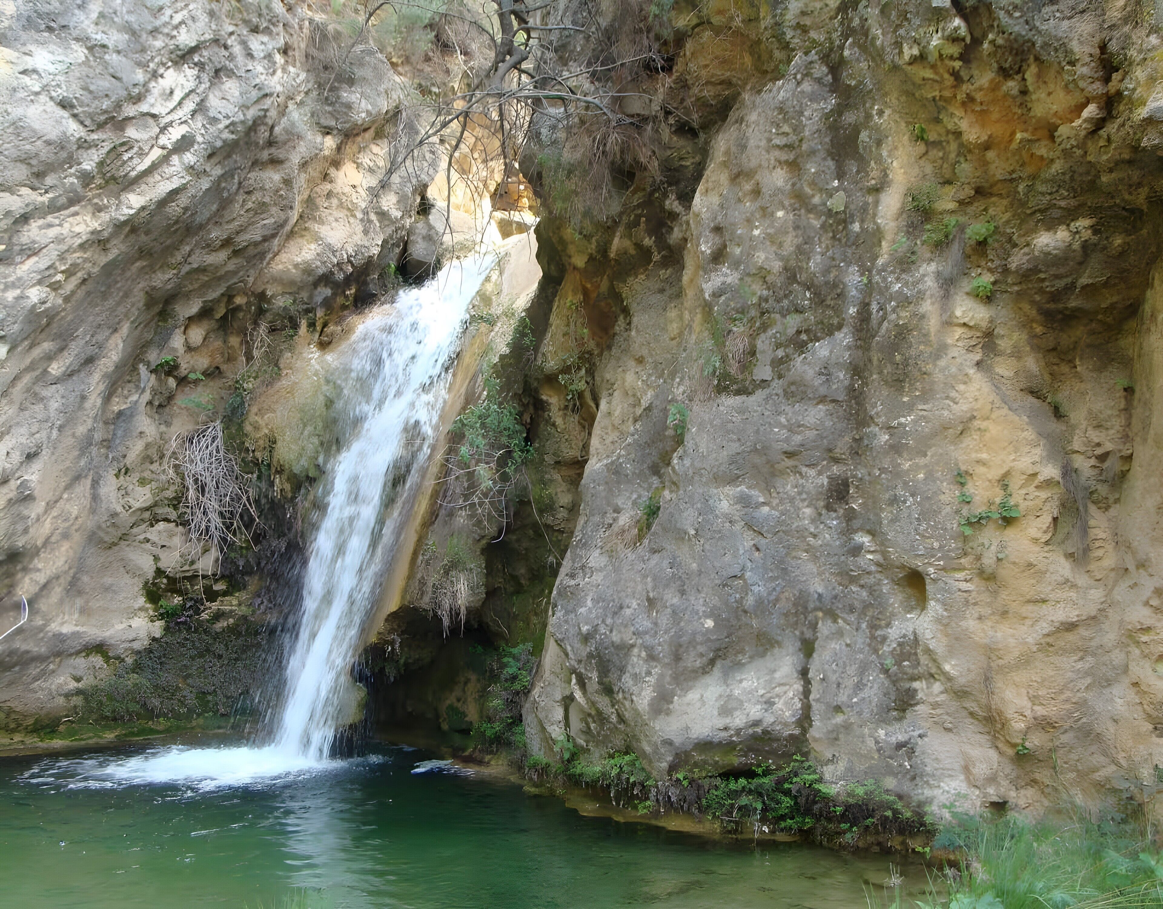A waterfall cascading into a pool surrounded by rocky cliffs.