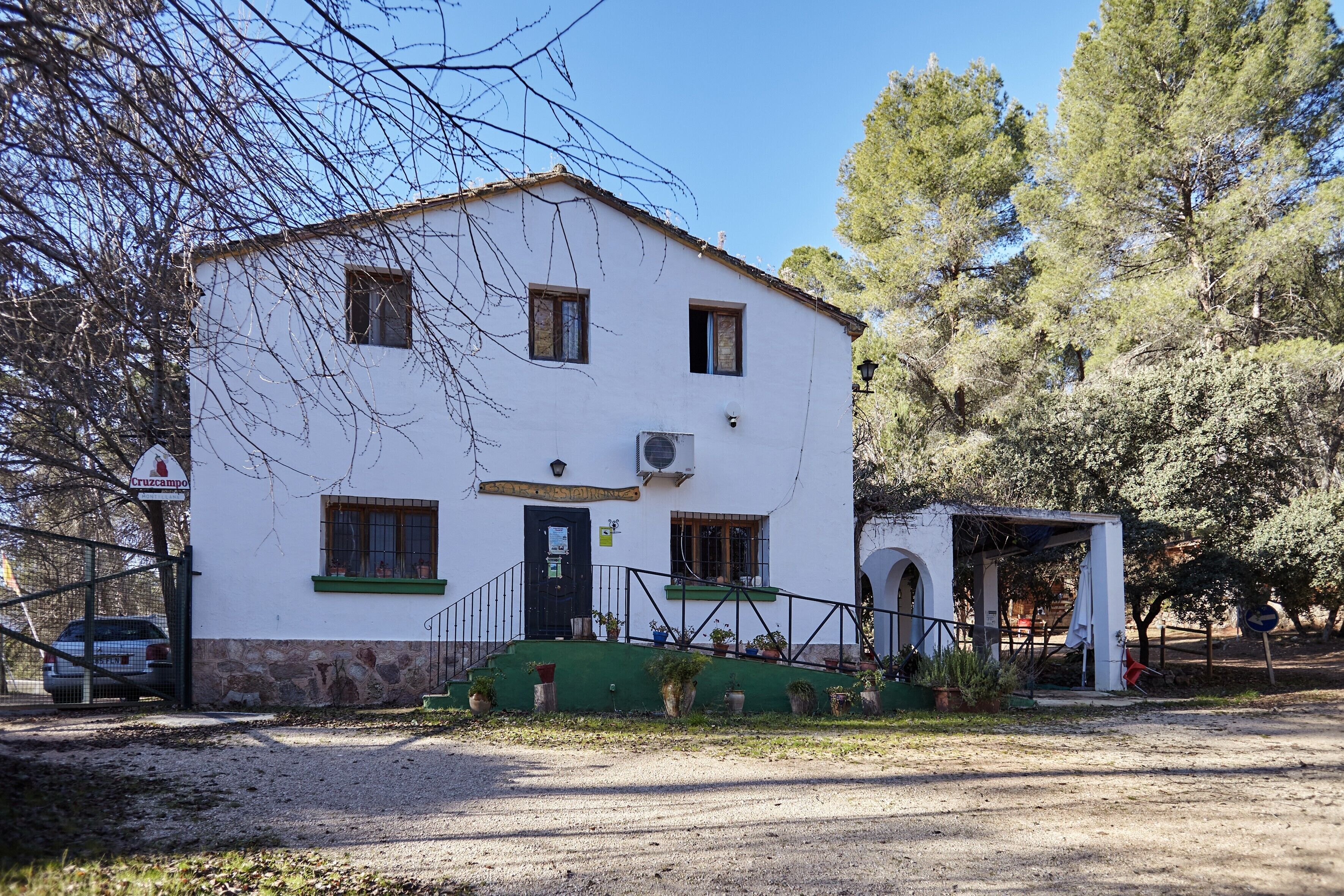 Ein weißes Gebäude mit schwarzem Eingang, einer kleinen Veranda und einem Schotterweg.
