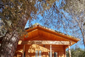 A wooden cabin with a covered porch, a visible door, and a sign reading 'El Charco'.