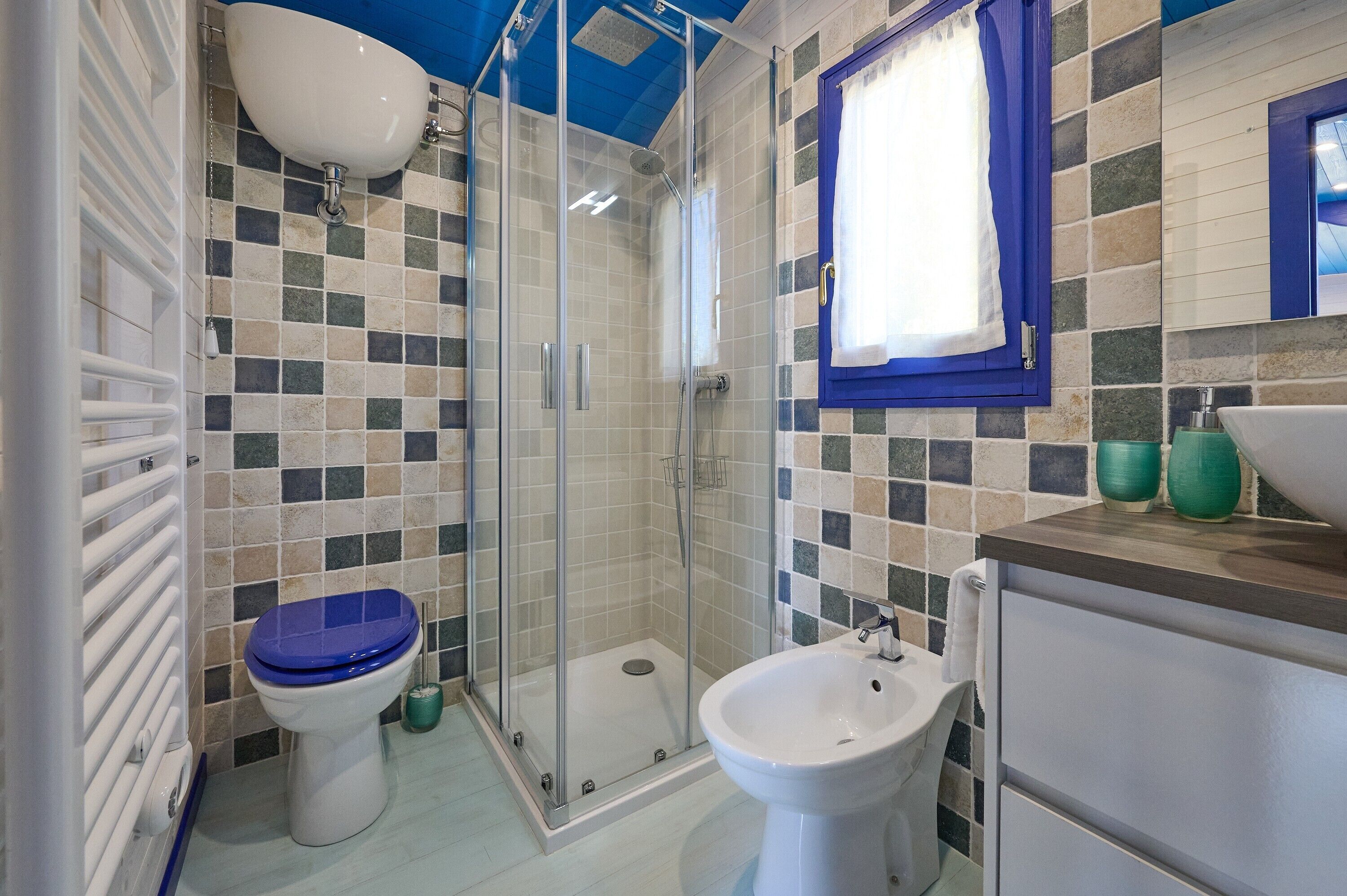 A bathroom with a shower, toilet, bidet, and a sink.