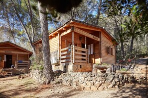 Eine rustikale Holzhütte mit Steinfundament, Holzfassade und einer Veranda mit Stühlen.